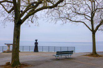 Waterfront with Bare Tree and Statue on Lake Neuchatel in Old Town in a Foggy Winter day in City of