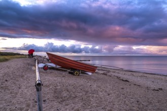 Atmospheric landscape on the Baltic Sea with a red boat and colourful clouds. Seaside with a red