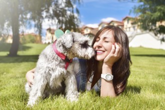 Pretty adult caucasian happy woman resting in the park on a sunny day with her beloved dog. Female
