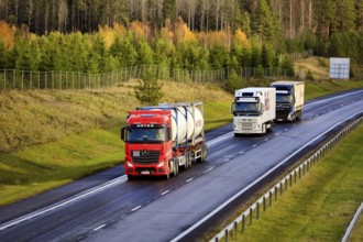Three freight trucks transporting load along freeway on a day of autumn, elevated view. Salo,