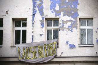 A sheet with a slogan hangs in front of a squatted flat in an old building in Berlin Kreuzberg
