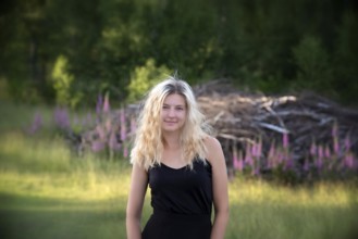 Portrait young blonde woman out and about in nature on a summer evening. Young woman with long