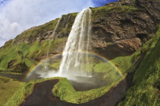 Summer sunny day. Large rainbow decorates a drop of water. Seljalandsfoss waterfall in Iceland. The