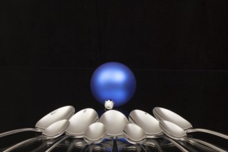 Blue Christmas decoration and nine spoons on a black glass desk