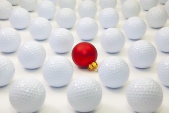 Pattern with white golf balls and red Christmas decoration on the table