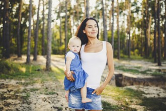 Young beautiful fashionable mother with long brunette hair holding a daughter's blonde with blue