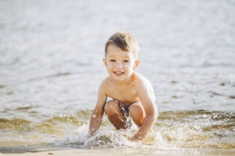Theme is summer time and rest near the water. Little joyful Caucasian funny boy plays and enjoys in