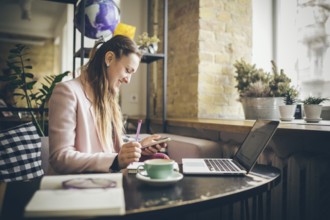 Successful business. Outsource. Woman blogger sits in cafe and uses smartphone, checks email,