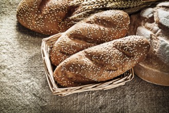 Wicker basket bread breadstick wheat ears on vintage burlap background