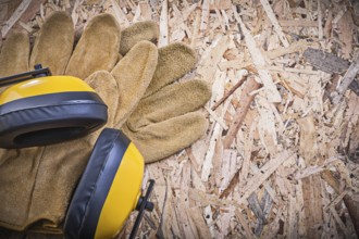 Safety leather gloves earmuffs on chipboard