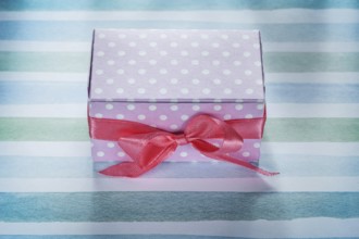 Pink present box on blue striped fabric top view holidays concept