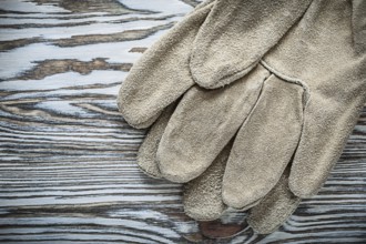 Pair of leather safety gloves on wooden board