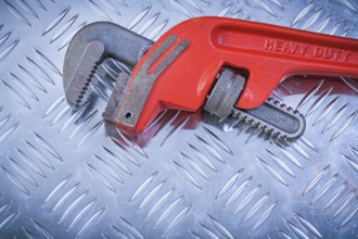 Metal monkey wrench on grooved metallic plate construction concept