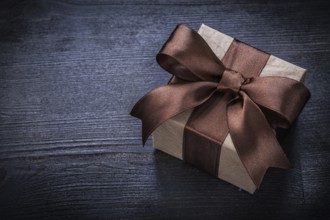 Boxed present with brown bow on vintage wood board copyspace