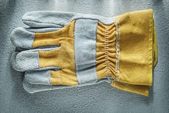 Pair of safety gloves on concrete background