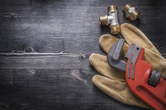 Monkey wrench brass plumbing fittings leather safety gloves construction concept