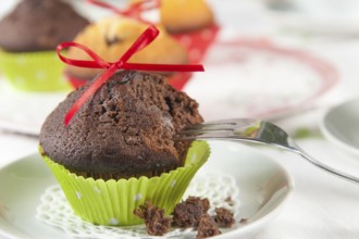 Lovingly decorated muffins on a coffee table. In the foreground, a chocolate muffin with a red bow