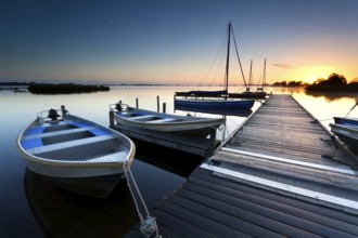 Sunrise over lake harbor with boats and pier
