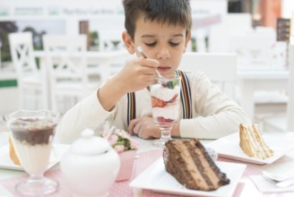 Child eat strawberry smoothie. Choco Cake on a table