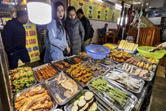 Visitors look at a rich selection of grilled food at a night market, restaurant in the streets of
