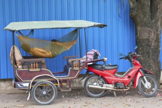 A Cambodian driver sleeps in hammock in his tuktuk