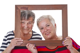 Two senior women looking through a picture frame Two senior women looking through a picture frame