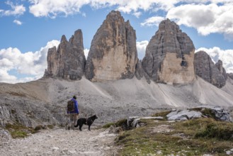 A female person hiking lonely with her dog around the Drei Zinnen mountains, the Dolomites in South