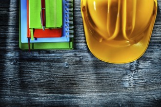 Set of notebooks pen hard hat on wooden board