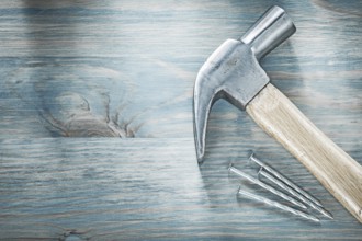 Claw hammer metal nails on wooden board top view construction concept
