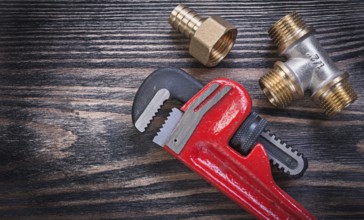 Pipe wrench brass equal tee nipple hose connector on wooden background plumbing concept