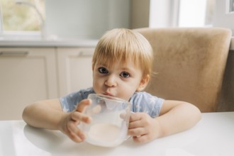 Portrait of happy little girl holding glass of milk, cute child drink fresh dairy product every day
