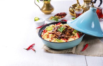 Tajin with couscous, vegetables and meat on a white background