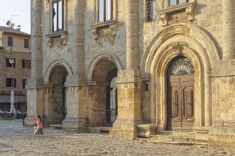 A tourist takes a photo into the sun on the Town Square Piazza Grande of Montepulciano, Tuscany,