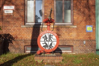 Fire brigade sign with fire pump in front of the building of the voluntary fire brigade in