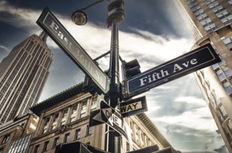 Fifth Ave 5th Ave, New York City sign, view from low angle with sunset and empire state building in