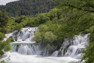 Several waterfalls flow through a lushly wooded hilly landscape, Krka Krka Waterfalls National