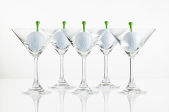 Five glasses of champagne and golf equipments on the glass desk