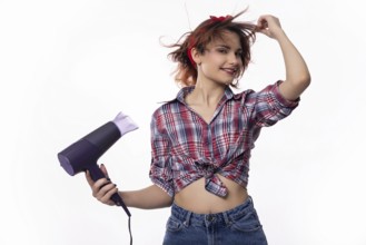 A playful young woman joyfully uses a hair dryer, delighting in her hairstyle with vibrant energy