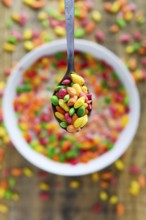 Spoon with colorful rice in the milk with blured background. Selective focus