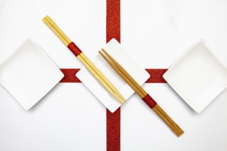 Ceramic bowls and bamboo chopsticks for sushi food with red and white decoration