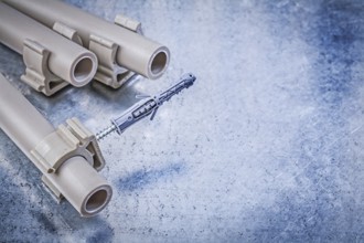 Plastic water pipe clamps on metallic background construction concept