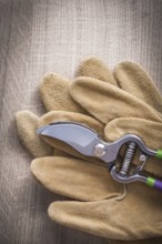 Sharp garden pruner and working leather safety gloves on wooden board agriculture concept