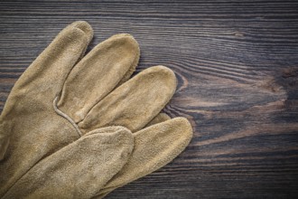 Pair of leather protective gloves on vintage wooden board agriculture concept
