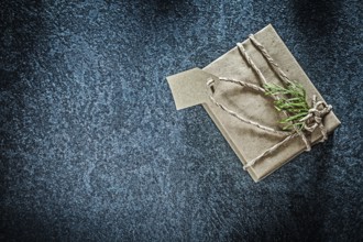 Wrapped gift box with thuya branch on black background holidays concept