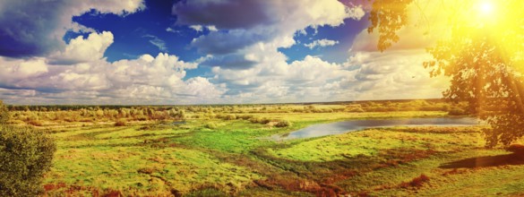 Panoramic view on big meadow with small flood sky with sun instagram stile