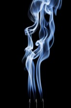 Delicate smoke plumes, puffs and eddies from burning incense sticks