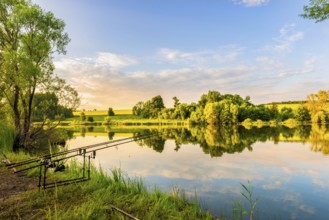 Fishing rods on a riverbank of calm river at sunset