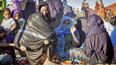 Gathering of people in colourful, traditional clothing in a desert landscape, woman at the