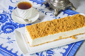 Professional bakery. Exquisite white cheesecake, sprinkled with sweet orange crumbs. The background
