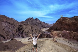 Lone tourist threw his hands up in delight in Eilat Mountains. Unique outcrops in the mountains of